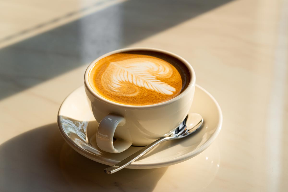 Vit kaffekopp och sked på bord